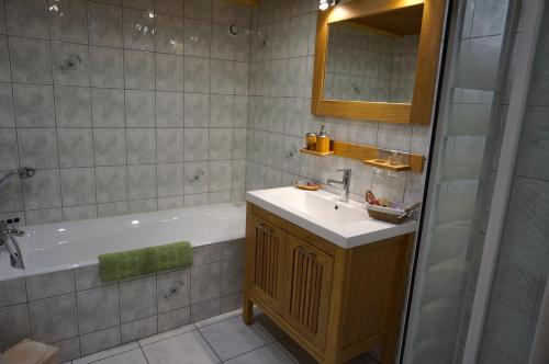 Un baño con lavabo, bañera y espejo. en Chalet Ancetre, en Morzine
