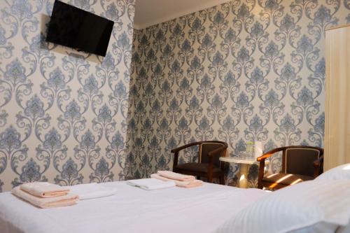 a bedroom with a bed and two chairs and a tv at Hotel Jasmina in Samarkand