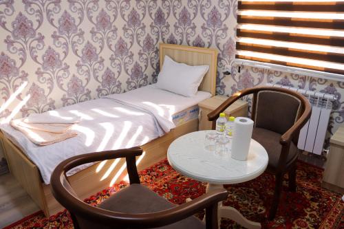 a small bedroom with a bed and a table and chairs at Hotel Jasmina in Samarkand