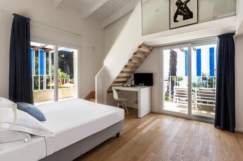 a white bedroom with a bed and a staircase at Calapetra Resort in Fontane Bianche