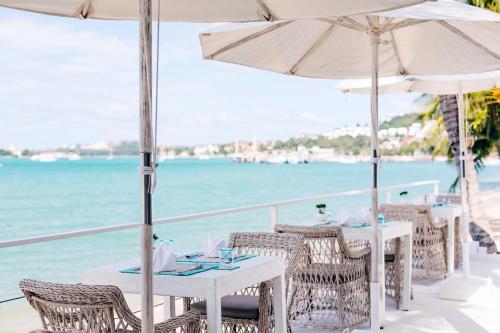 a restaurant with tables and umbrellas on the beach at Tembo Beach Club & Resort in Koh Samui 