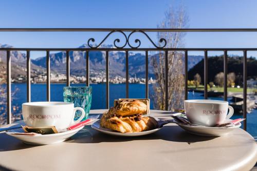 a table with two cups of coffee and a plate of food at LUXURY SUITES ROCOPOM - Lake Front in Lecco