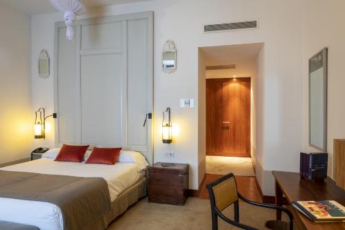 a bedroom with a bed and a desk and a television at Parador de La Granja in La Granja de San Ildefonso