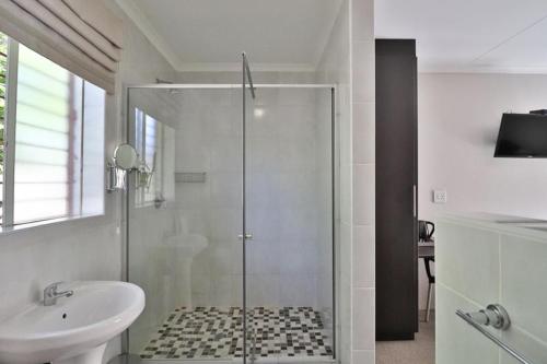 a bathroom with a glass shower and a sink at Fin and Feather Guest Lodge in Boksburg