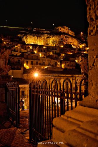 a view of a city at night with a fence at Si-Moutique, le Case-grotte degli Avi 2 in Modica