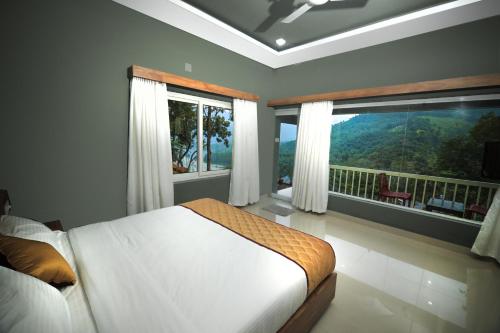 a bedroom with a bed and a balcony with windows at Casa Lucio Resorts in Mannārakkāt