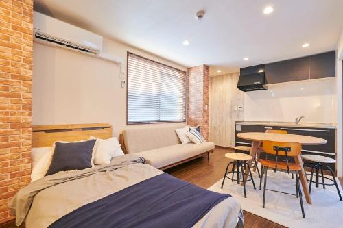 a bedroom with a bed and a table and a couch at 王子神谷ハウス OJIKAMIYA HOUSE in Tokyo