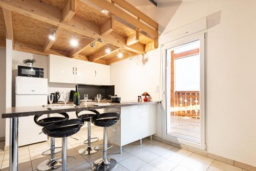 une cuisine avec des placards blancs et un comptoir avec des tabourets de bar dans l'établissement Bellevue, à La Bresse