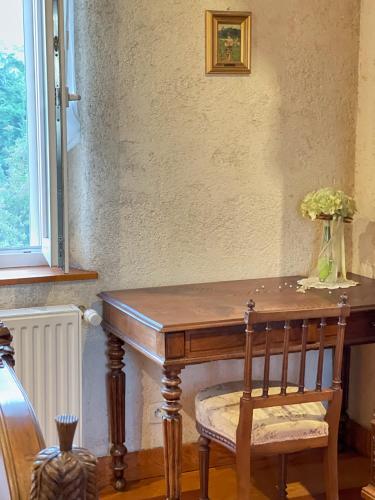 a wooden table with a chair and a vase of flowers at Chambres d'Hôtes Le Bourdieu in Soulignac