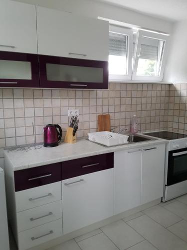 a kitchen with white cabinets and a counter top at Apartman Aladin in Bihać