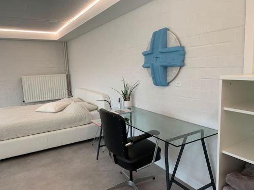 1 dormitorio con escritorio, 1 cama y una cruz azul en la pared en PARK Loft @ BRUGES with private (free) parking, en Brujas