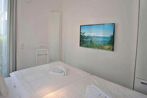 Biała sypialnia z 2 łóżkami i zdjęciem na ścianie w obiekcie Villa Poseidon - WE 5 in Strandnähe und zentrumsnah w mieście Binz