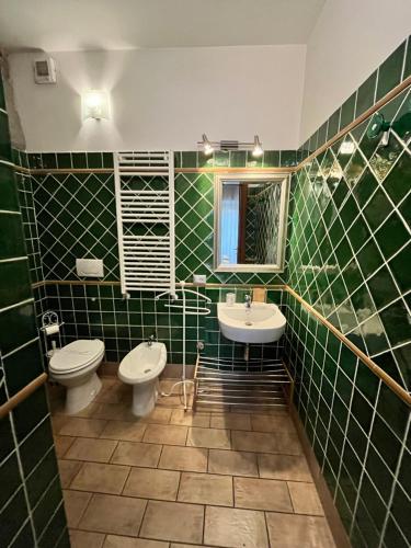 a green tiled bathroom with a toilet and a sink at Medieval House in Viterbo