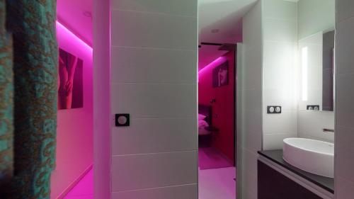 een badkamer met roze verlichting en een witte wastafel bij Village Naturiste Cap d'Agde, Studio Luxe Port Nature 7 in Cap d'Agde