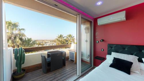 a bedroom with a bed and a balcony with a cactus at Village Naturiste Cap d'Agde, Studio Luxe Port Nature 7 in Cap d'Agde