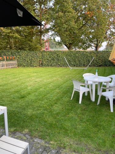a group of white tables and chairs on a lawn at B&B Maison Saint Tropez Eindhoven in Eindhoven