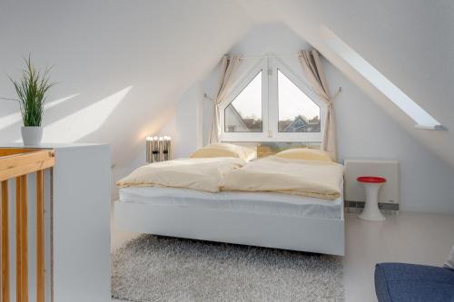 ein weißes Schlafzimmer mit einem Bett und einem Fenster in der Unterkunft Doppelhaushälfte "Am Krug" in Börgerende-Rethwisch