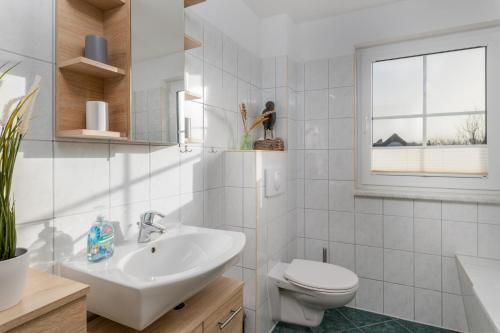 ein weißes Bad mit einem Waschbecken und einem WC in der Unterkunft Doppelhaushälfte "Am Krug" in Börgerende-Rethwisch