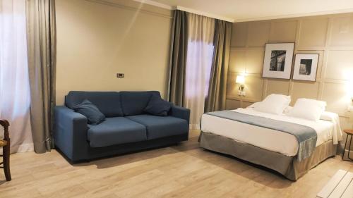 a bedroom with a bed and a blue couch at Hotel Doña Blanca in Jerez de la Frontera