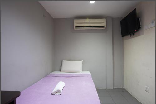 a small room with a bed with a purple blanket at T-Hotel Bukit Bintang in Kuala Lumpur