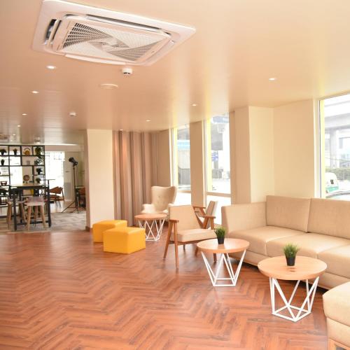 a living room with a couch and tables and chairs at Bloom - Golf Course Road in Gurgaon