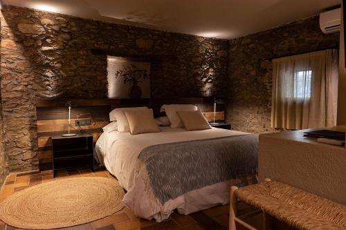 a bedroom with a bed and a stone wall at Can Barrina in Montseny