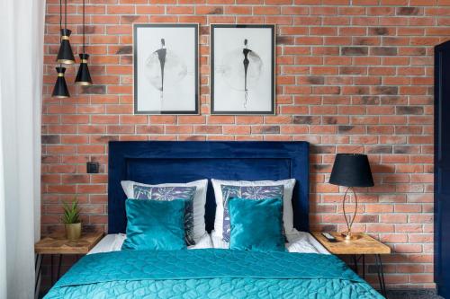 a bedroom with a blue bed and a brick wall at Przystań Stegna in Stegna