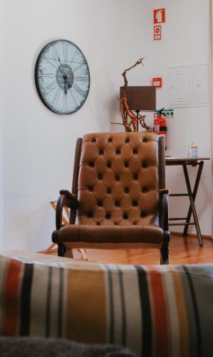 a chair in a living room with a clock on the wall at Quinta de Fiães in Vilar de Maçada