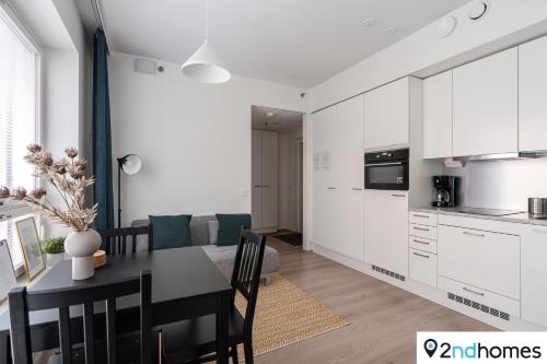 a kitchen and dining room with white cabinets and a table at 2ndhomes Tampere "Areena" Apartment in Tampere