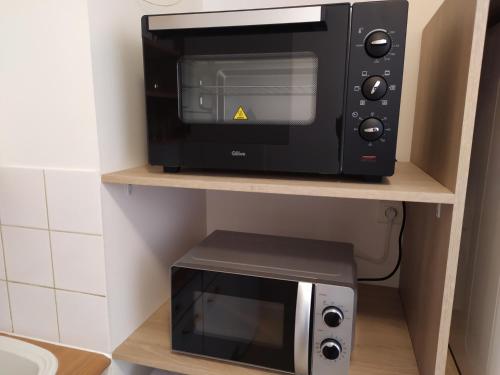 Un four micro-ondes est installé sur une étagère à côté d'un grille-pain. dans l'établissement T1 Bis Cosy avec 6 couchages proche de la mer - Quartier Minimes, à La Rochelle