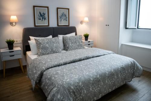 a bedroom with a bed with a gray comforter and pillows at Apartamentos Nueva Ribera in El Puerto de Santa María