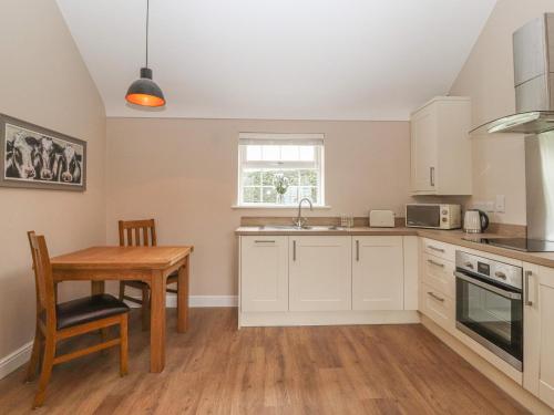 a kitchen with white cabinets and a wooden table at The Hay Barn in Chester