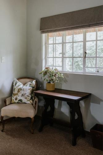 a chair sitting next to a table and a window at Breathe River Retreat in Parys