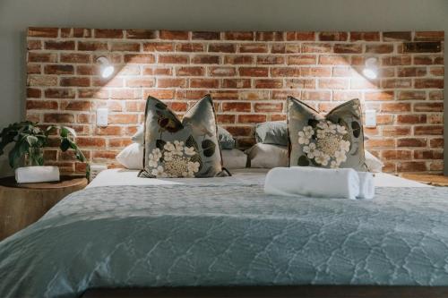 1 dormitorio con 1 cama con pared de ladrillo en Breathe River Retreat en Parys