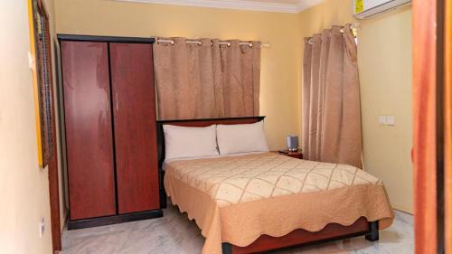 a small bedroom with a bed and wooden cabinets at LaV ROYAL HOTEL in Kumasi