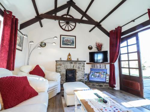 a living room with white couches and a fireplace at Y Stabl in Fishguard
