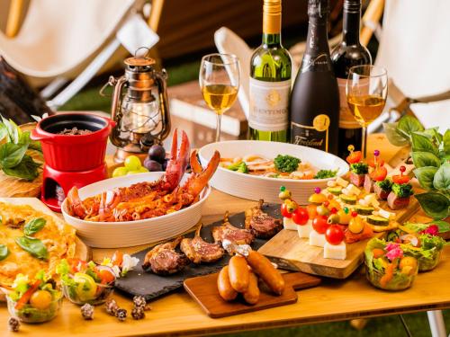 a table topped with plates of food and glasses of wine at A-GATE HOTEL 旭川 -Asahikawa- in Asahikawa