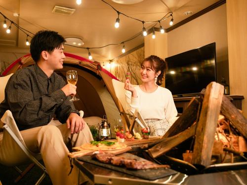 um homem e uma mulher sentados à mesa com um copo de vinho em A-GATE HOTEL 旭川 -Asahikawa- em Asahikawa
