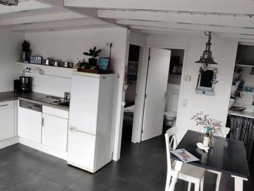 een keuken met een witte koelkast en een tafel bij Cosy vacation home near the beach in Egmond aan Zee