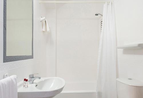 La salle de bains blanche est pourvue d'un lavabo et d'une douche. dans l'établissement Hotel Base - Adults Only, à Sant Antoni de Portmany