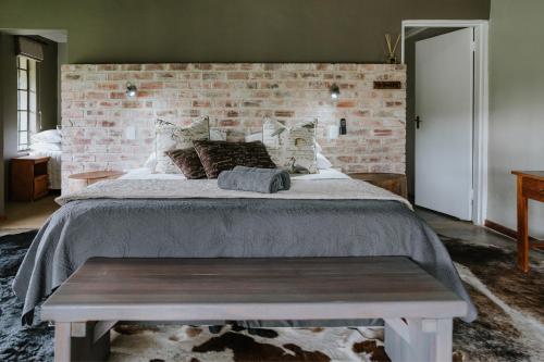 a bedroom with a large bed with a brick wall at Breathe River Retreat in Parys