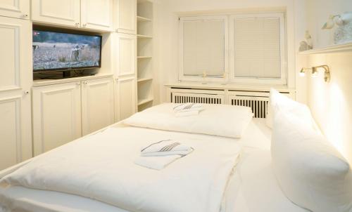 ヴェスターラントにあるGuenzburg-3-Wohnung-Muschelsucher-Kampstr-9の白いベッド(枕2つ付)、テレビが備わります。