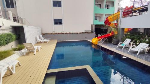 a swimming pool with chairs and an umbrella and a water slide at Baan Manthana House in Hua Hin