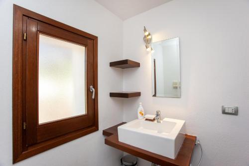 un bagno con un lavandino bianco e uno specchio di Hora Frisca a Orosei