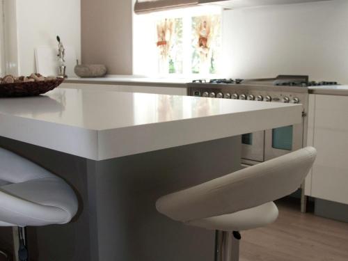 a kitchen with a white island with stools at Mansion in Nijensleek with Sauna & Garden in Nijensleek