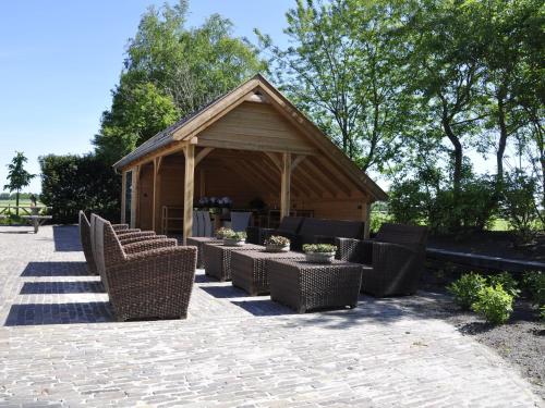 a pavilion with wicker chairs and tables in front of a building at Mansion in Nijensleek with Sauna & Garden in Nijensleek