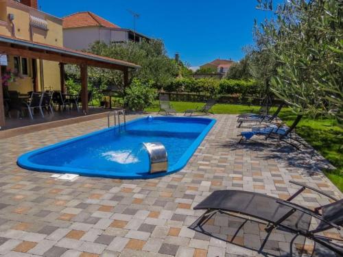 una piscina in un cortile con sedie intorno di Captivating Holiday Home in Pako tane with Swimming Pool a Pakoštane