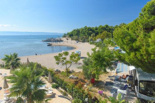 a view of a beach with palm trees and a bus at Camping Stobreč Split in Split