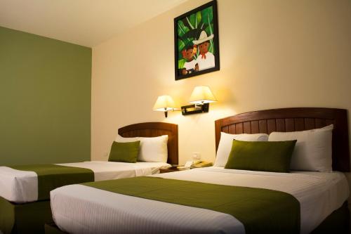 2 camas en una habitación de hotel con paredes verdes en Tabasco Inn, en Villahermosa