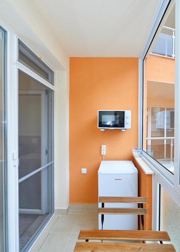 um quarto com uma parede laranja, um frigorífico e uma televisão em Студио Патрисия em Pomorie